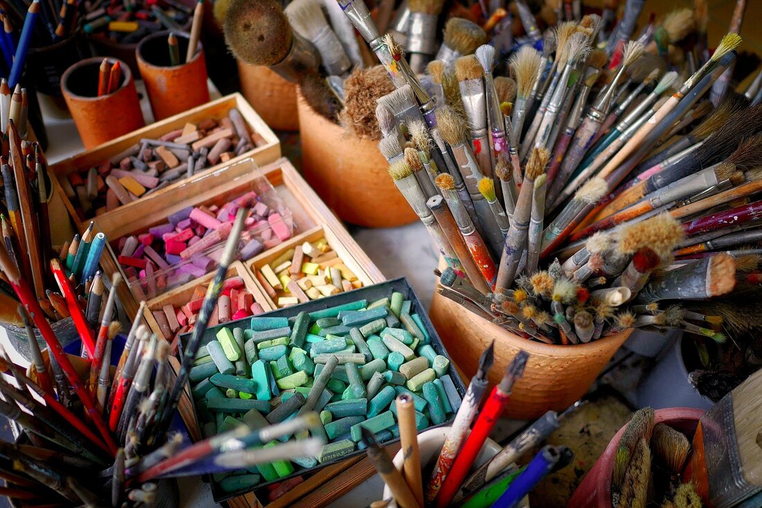 Desk in atelier filled with bold coloured artsupplies